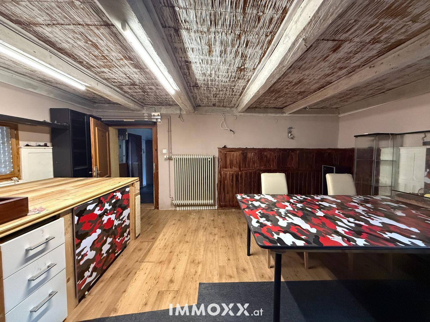Innenraum mit Holzdecke, Holzboden und einem Tisch mit auffälligem Muster.