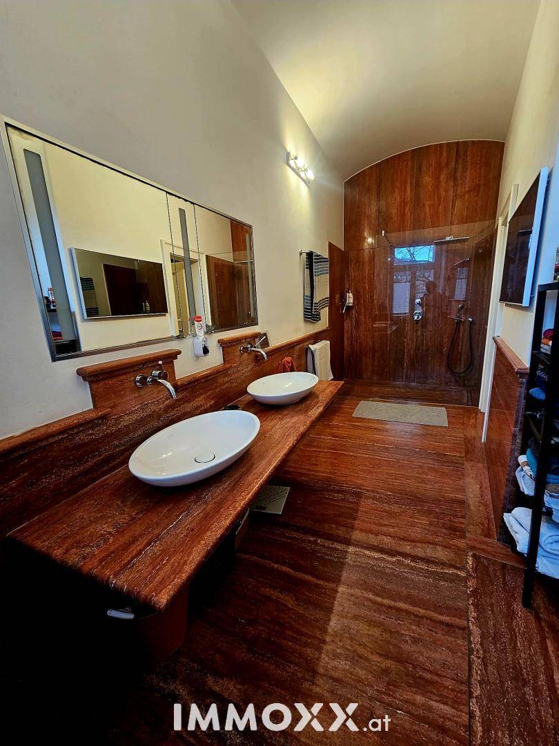 Modernes Badezimmer mit doppelten Waschbecken, begehbarer Dusche und Holzakzenten.