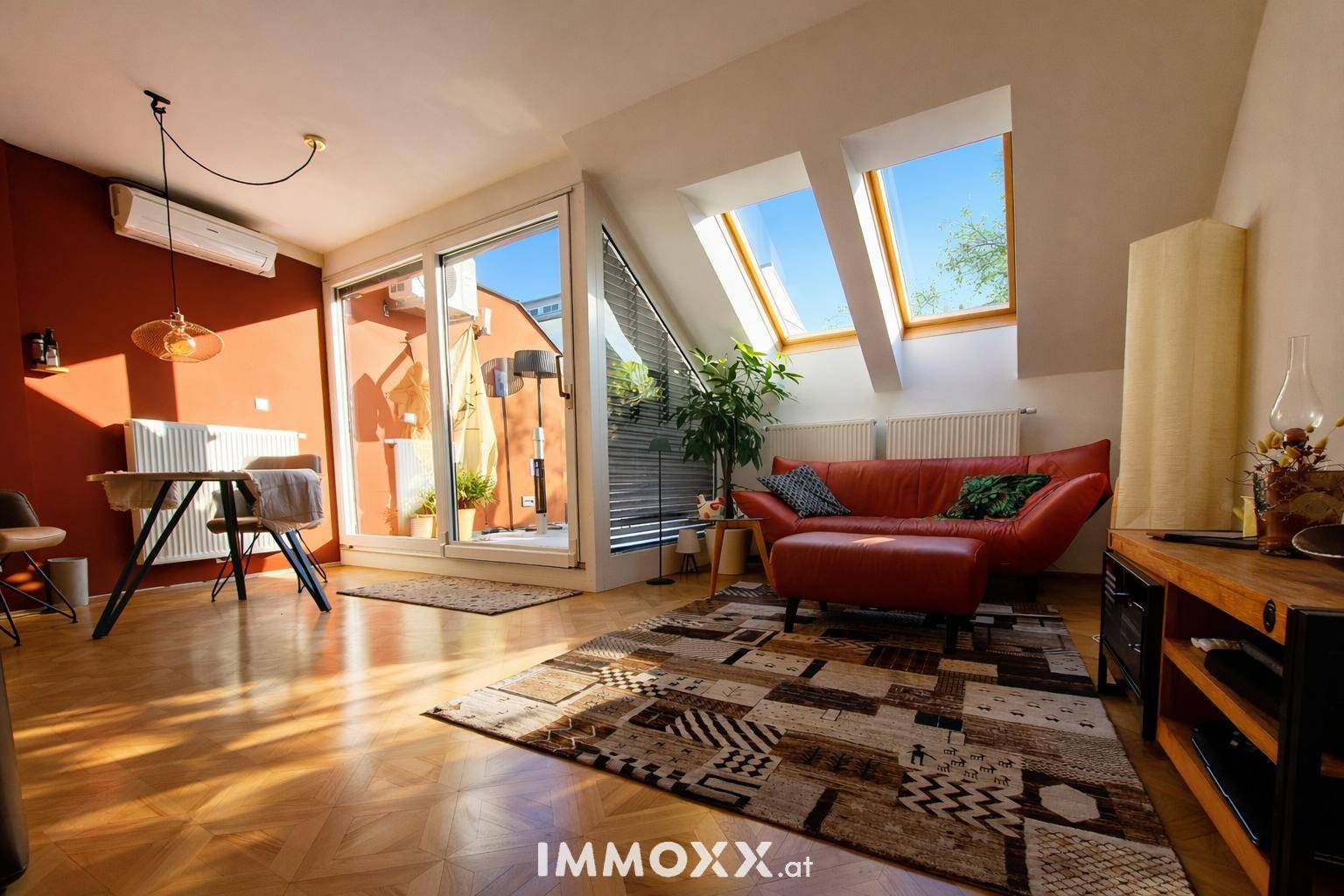 Helles Wohnzimmer mit Parkettboden, Dachfenstern und Zugang zu einer kleinen Terrasse.