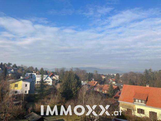 Panoramablick über eine Wohngegend mit vielfältiger Bebauung und bewaldeten Hügeln am Horizont.