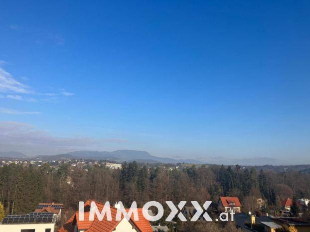 Klarer Blick auf die weite Landschaft mit Bergen und bewaldeten Gebieten unter strahlend blauem Himmel.