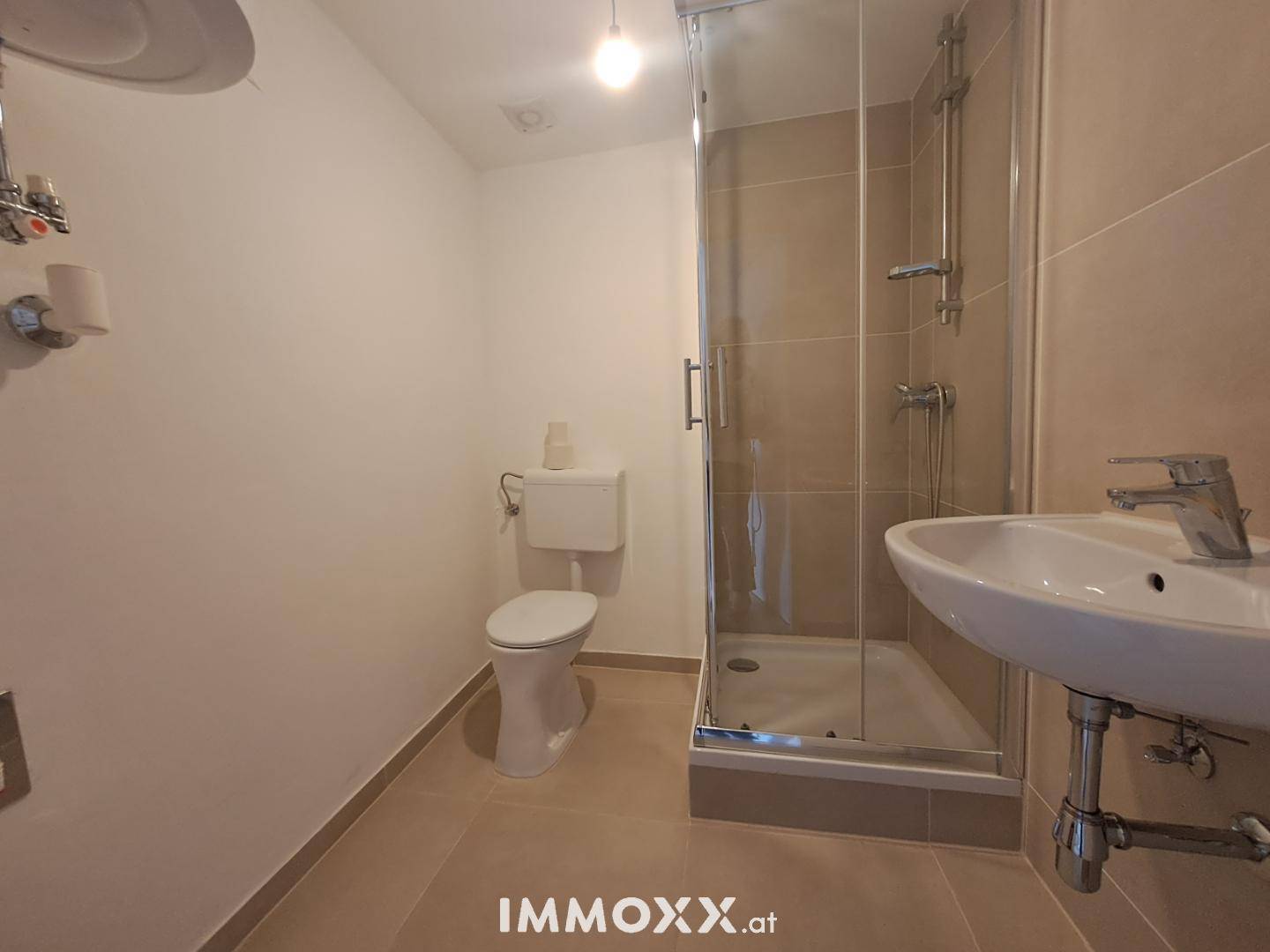 Helles Badezimmer mit Duschkabine, WC und Waschbecken, ausgestattet mit modernen Fliesen.