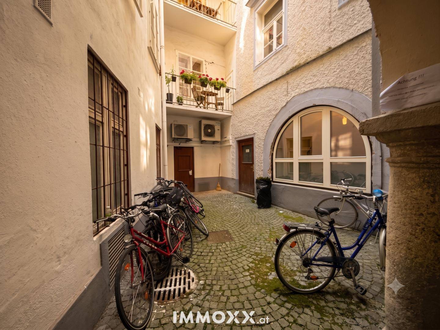 Historischer Innenhof mit Kopfsteinpflaster und abgestellten Fahrrädern, umgeben von Altbaufassaden.