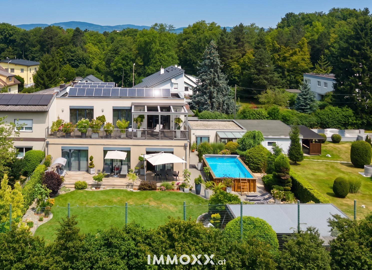 Weitläufiger Gartenbereich mit Pool und moderner Architektur des Hauses unter blauem Himmel.