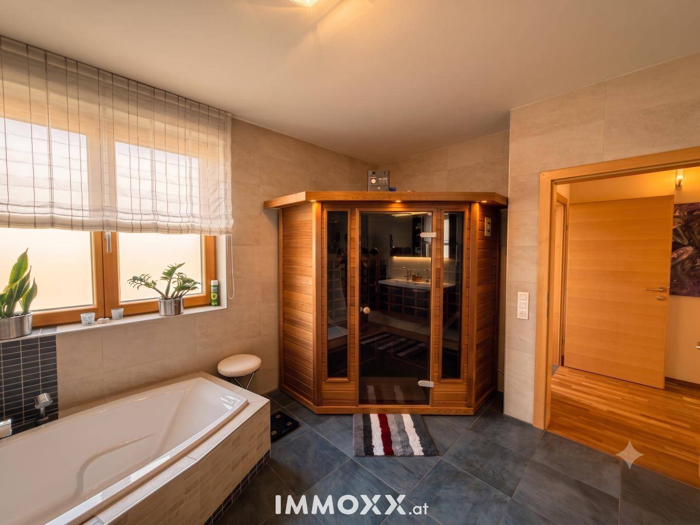 Modernes Badezimmer mit Badewanne, Dusche und integrierter Sauna für Wellnessmomente.