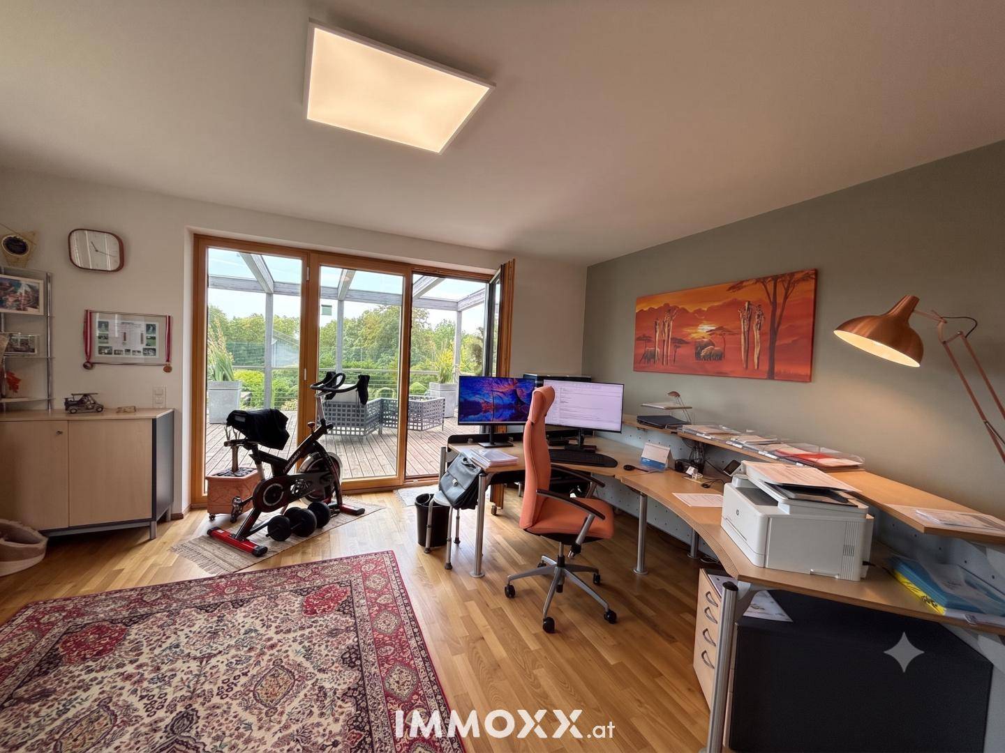 Helles Arbeitszimmer mit Holzboden, Schreibtisch und Zugang zur Terrasse.