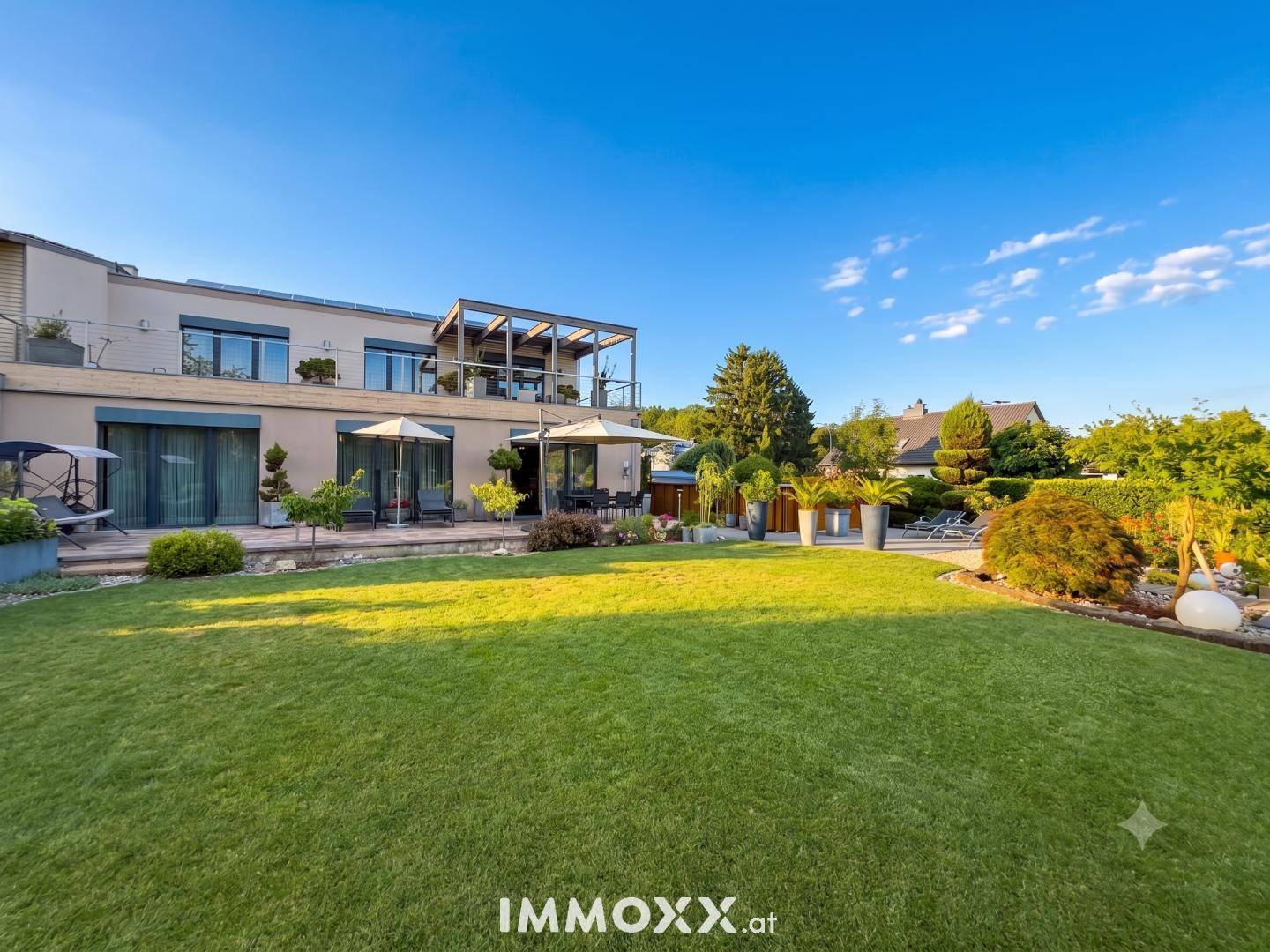 Gepflegter Rasen und Gartenbereich mit Blick auf die moderne Hausfassade und Terrassen.