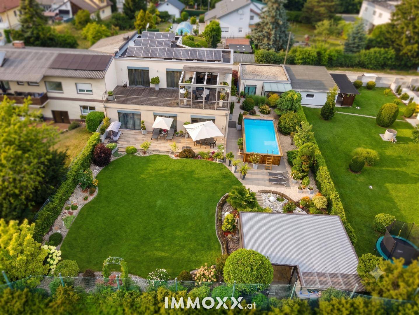 Luftaufnahme des Anwesens mit großem Garten, Pool, Solaranlage und umliegender Nachbarschaft.