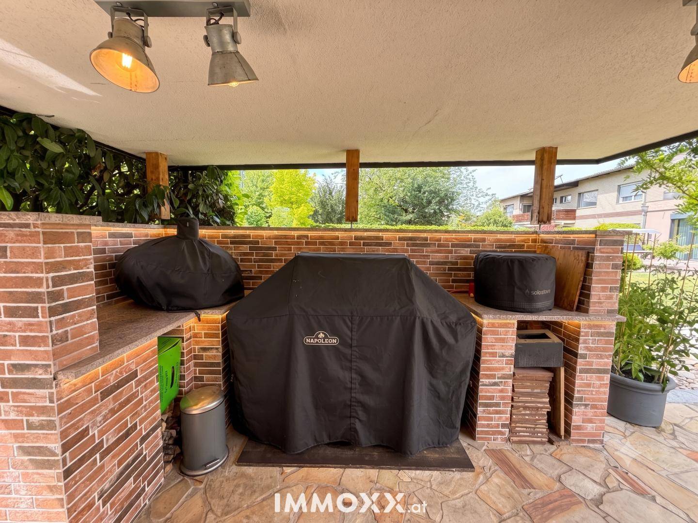 Überdachter Grillbereich mit gemauertem Tresen und professionellen Grillgeräten.