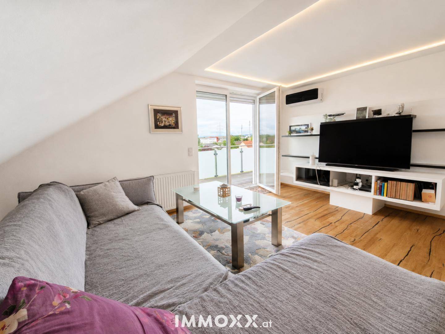Helles Wohnzimmer im Dachgeschoss mit Zugang zur Terrasse und moderner TV-Wand.