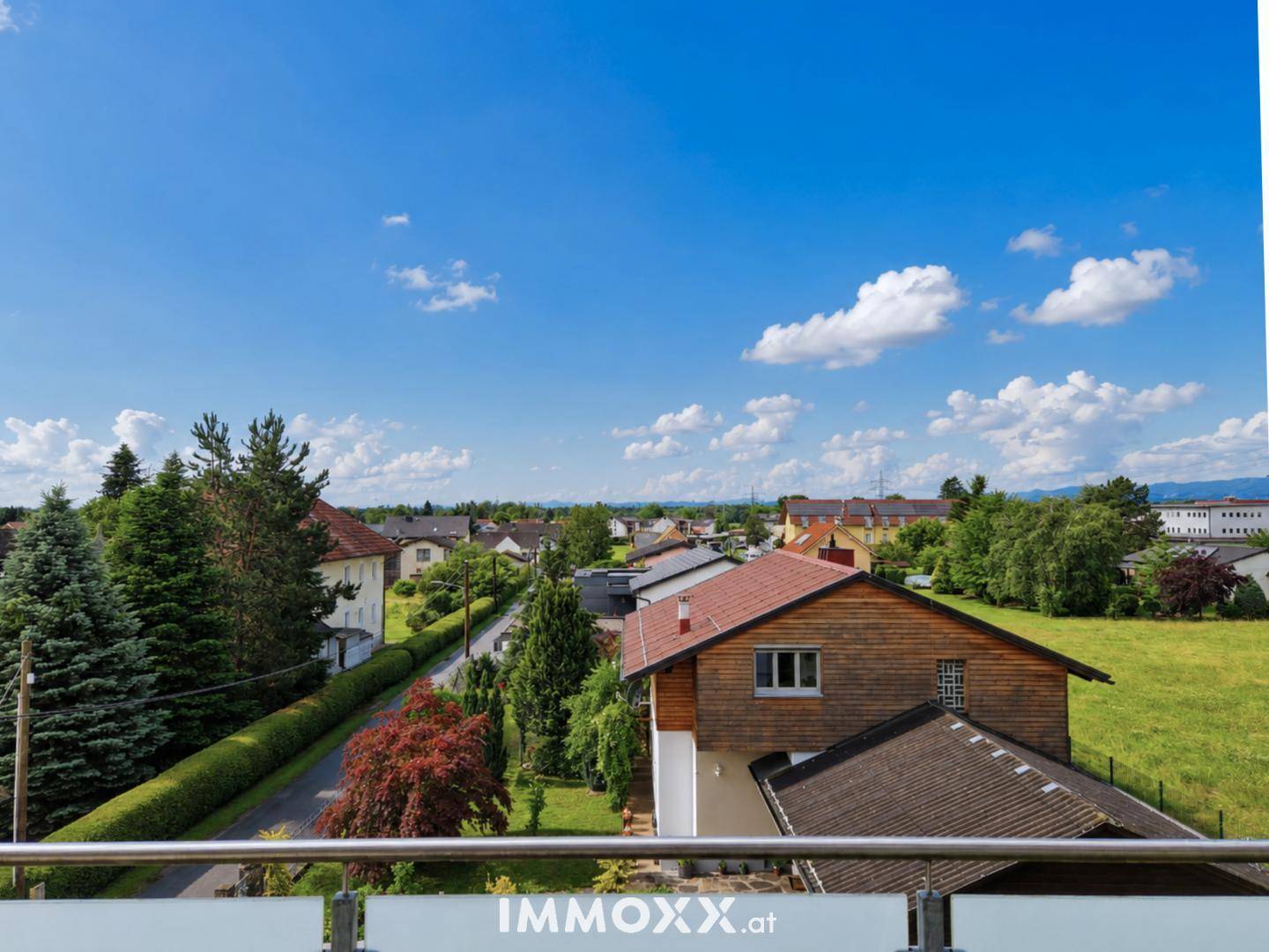 Weitläufiger Blick vom Balkon über die umliegende Wohngegend mit viel Grün und Häusern.
