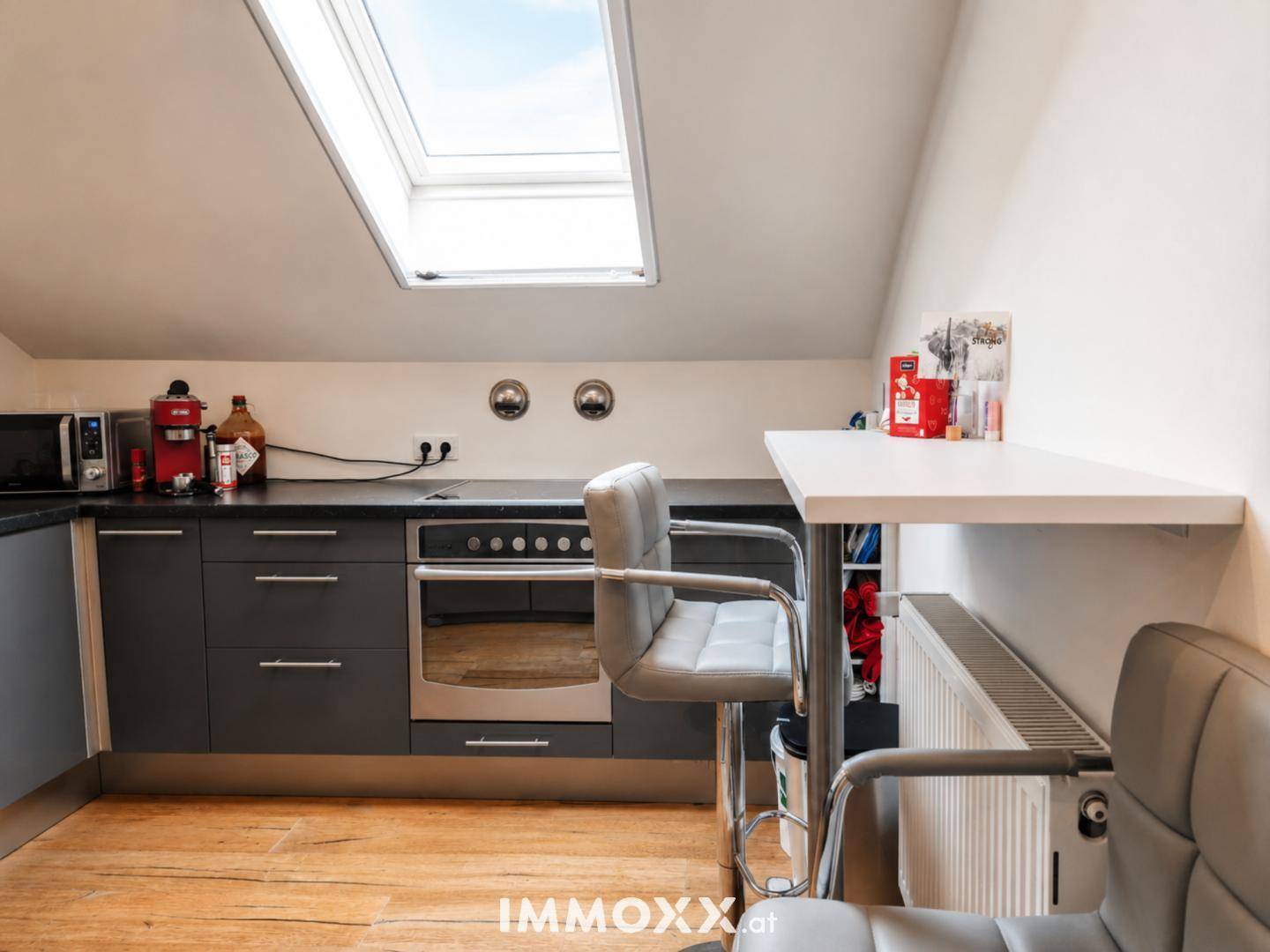 Küchenzeile im Dachgeschoss mit integriertem Backofen, Barhocker und praktischer Arbeitsfläche.