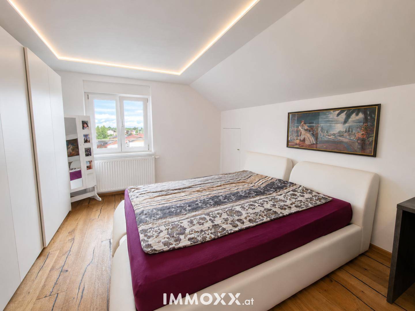 Modernes Schlafzimmer im Dachgeschoss mit Doppelbett, Einbauschränken und Holzboden.