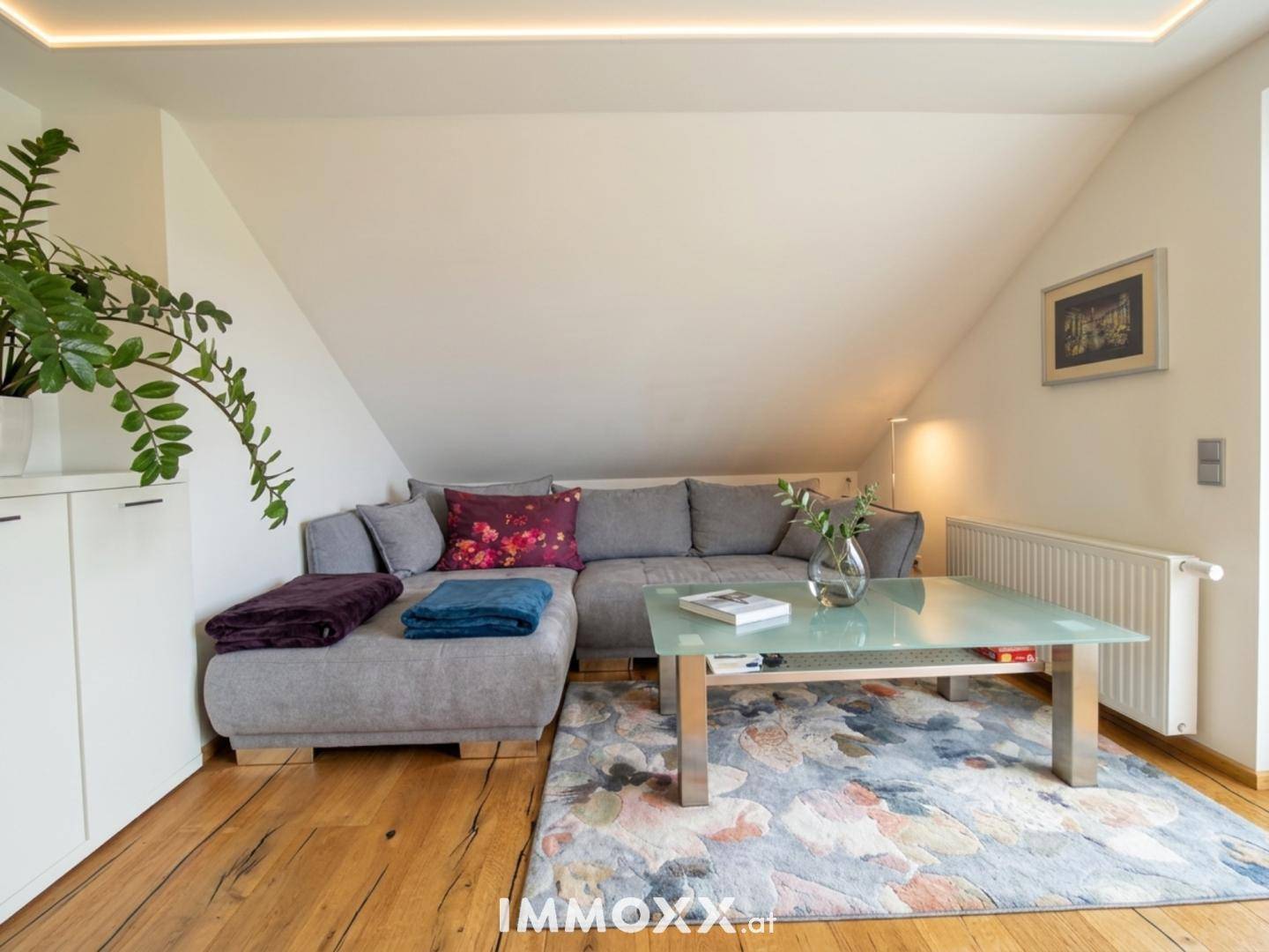 Gemütliches Wohnzimmer im Dachgeschoss mit Ecksofa, Couchtisch und Holzboden.