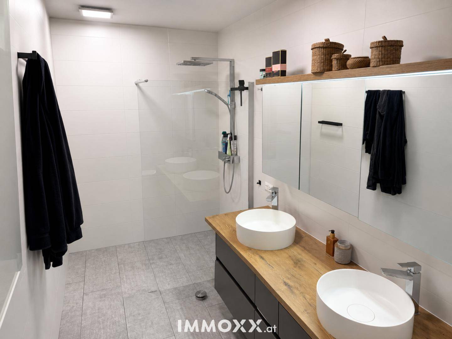 Modernes Badezimmer mit begehbarer Dusche, Doppelwaschbecken und Holzdetails.