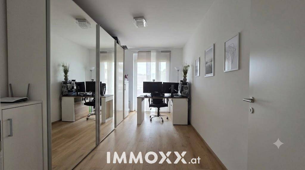 Modernes Arbeitszimmer mit zwei Schreibtischen und großem Spiegelschrank.