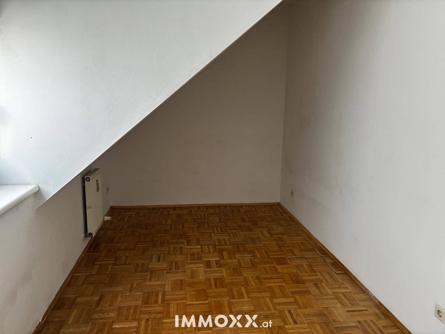 Kleiner Raum mit schräger Decke und Parkettboden, ideal als Abstellraum oder kleines Arbeitszimmer.