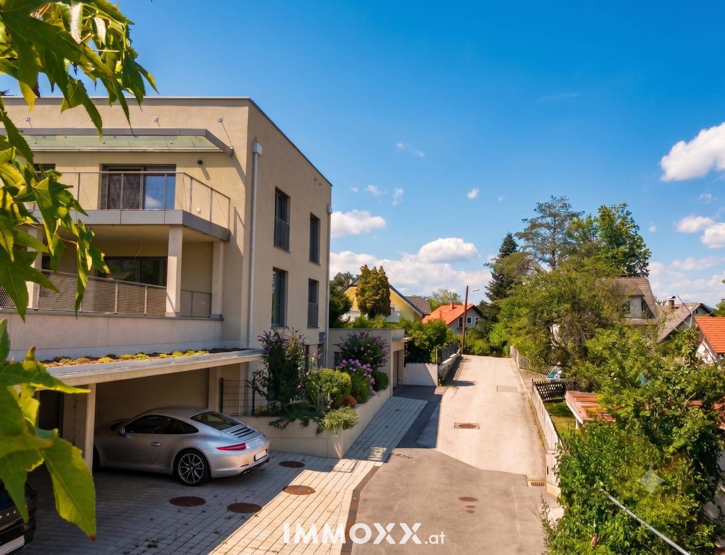 Ansicht der modernen Wohnanlage von der Straße mit Carport und Balkonen.