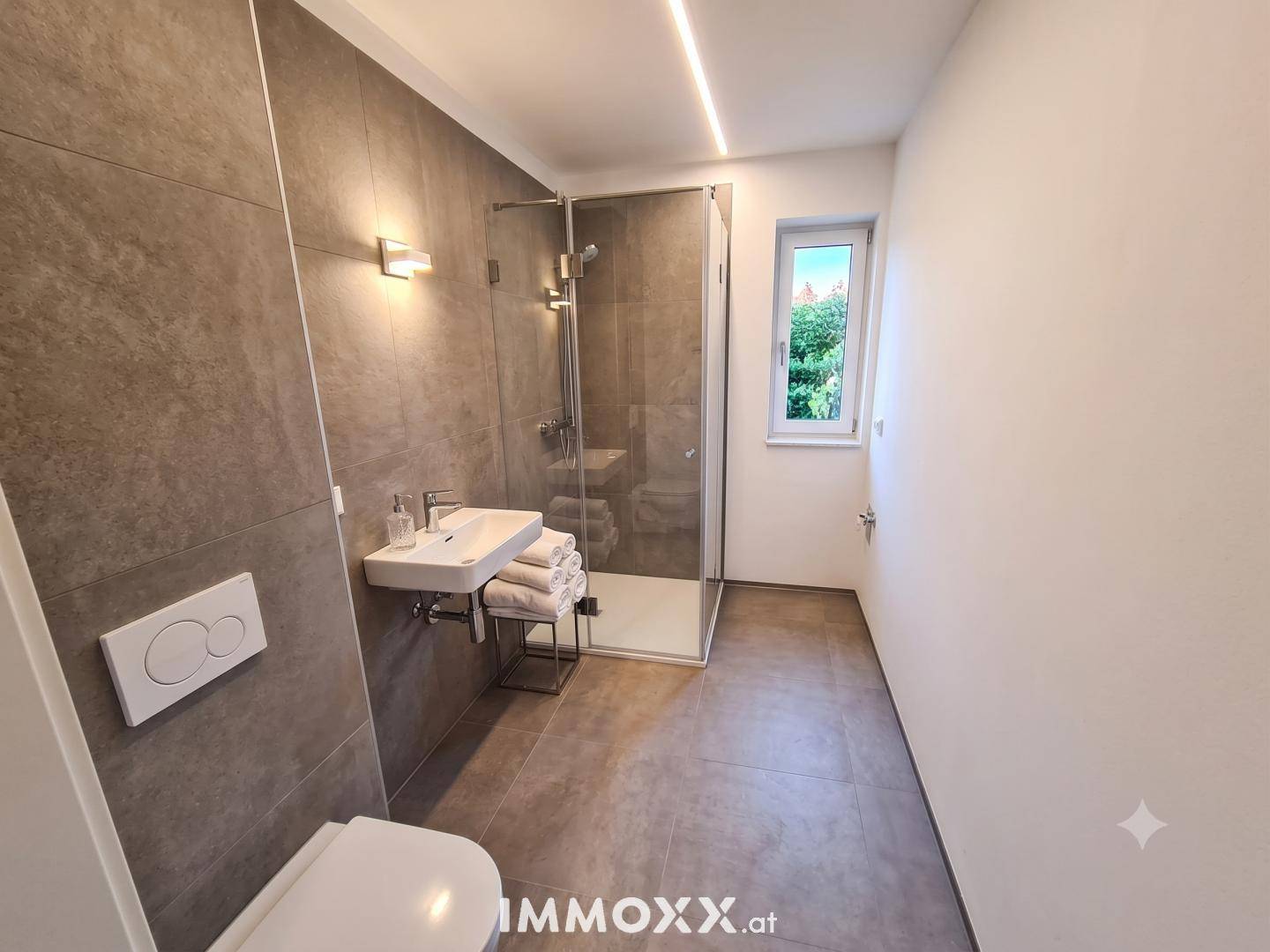 Modernes Badezimmer mit begehbarer Dusche, Wand-WC und großformatigen Fliesen.