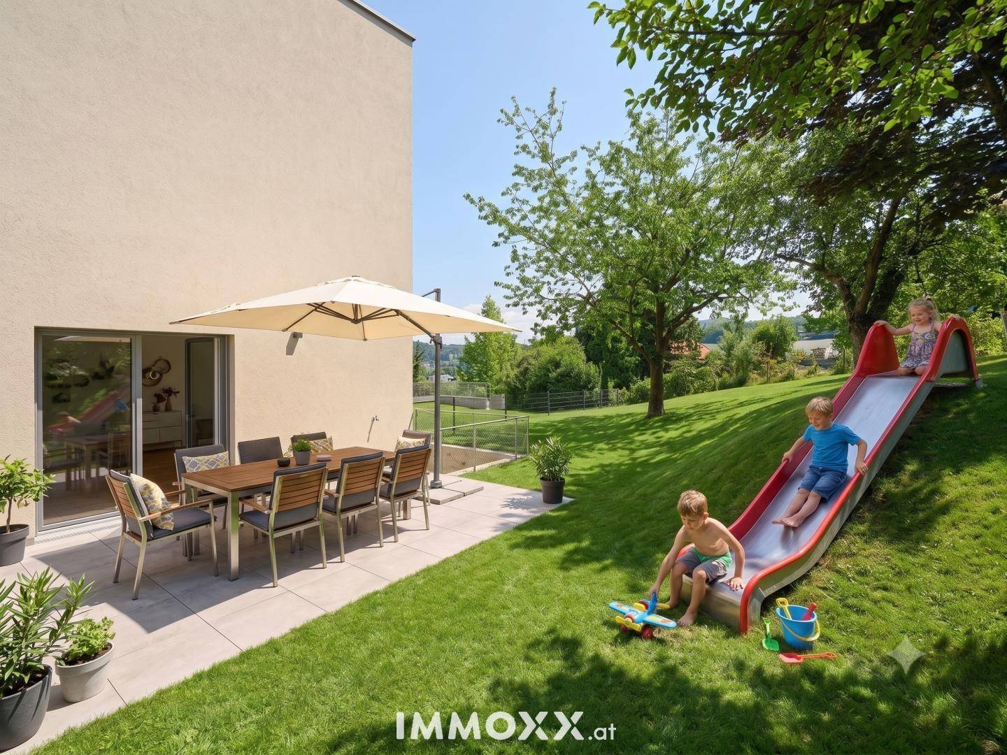 Sonniger Garten mit Terrasse, Esstisch und Spielbereich für Kinder mit Rutsche und Rasenfläche.