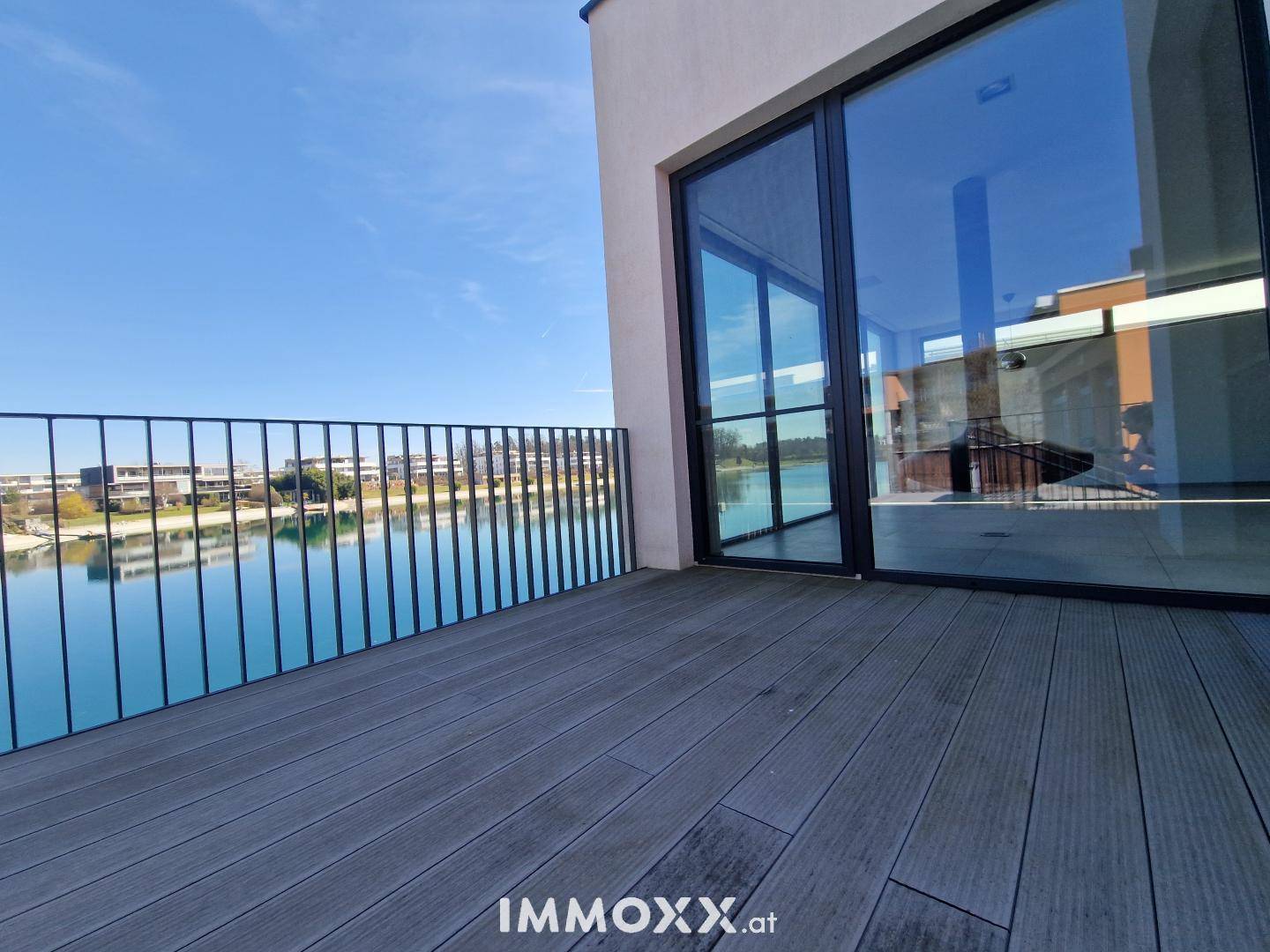 Balkon mit Glasfront und Metallgeländer bietet einen weiten Blick über den See und die Umgebung.