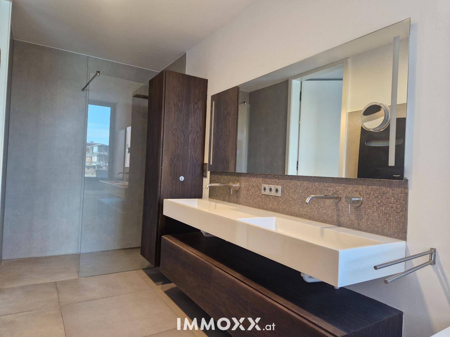 Luxuriöses Badezimmer mit Doppelwaschbecken, großem Spiegel und begehbarer Dusche.