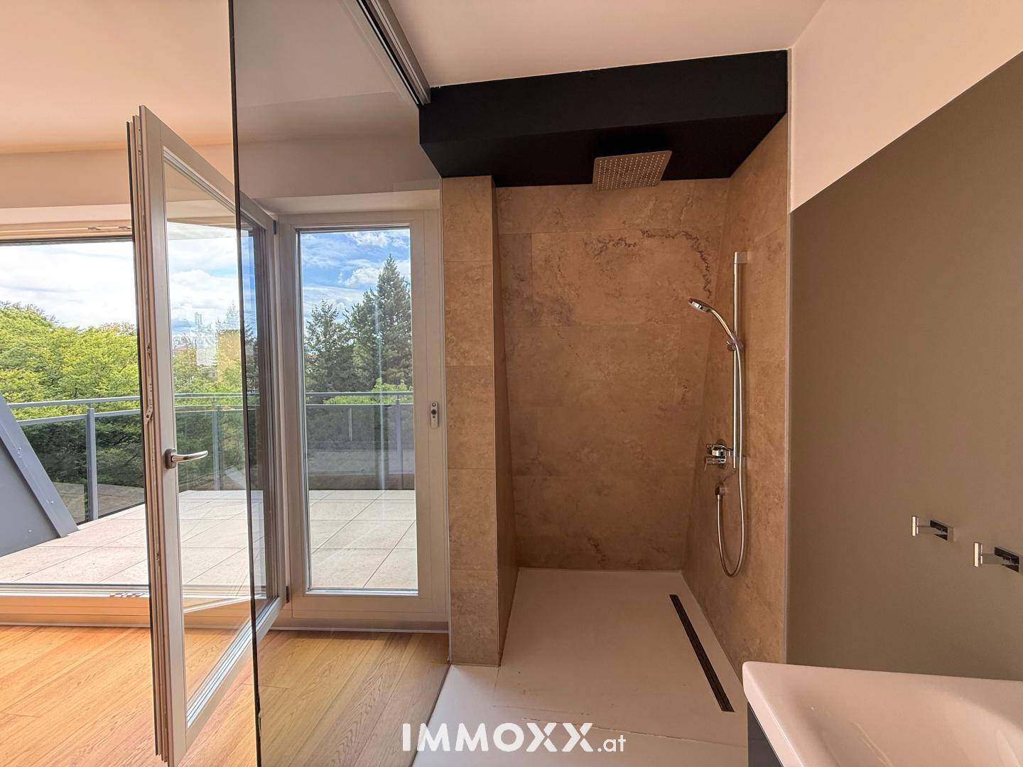 Modernes Badezimmer mit begehbarer Dusche, Regenduschkopf und direktem Zugang zur Terrasse.