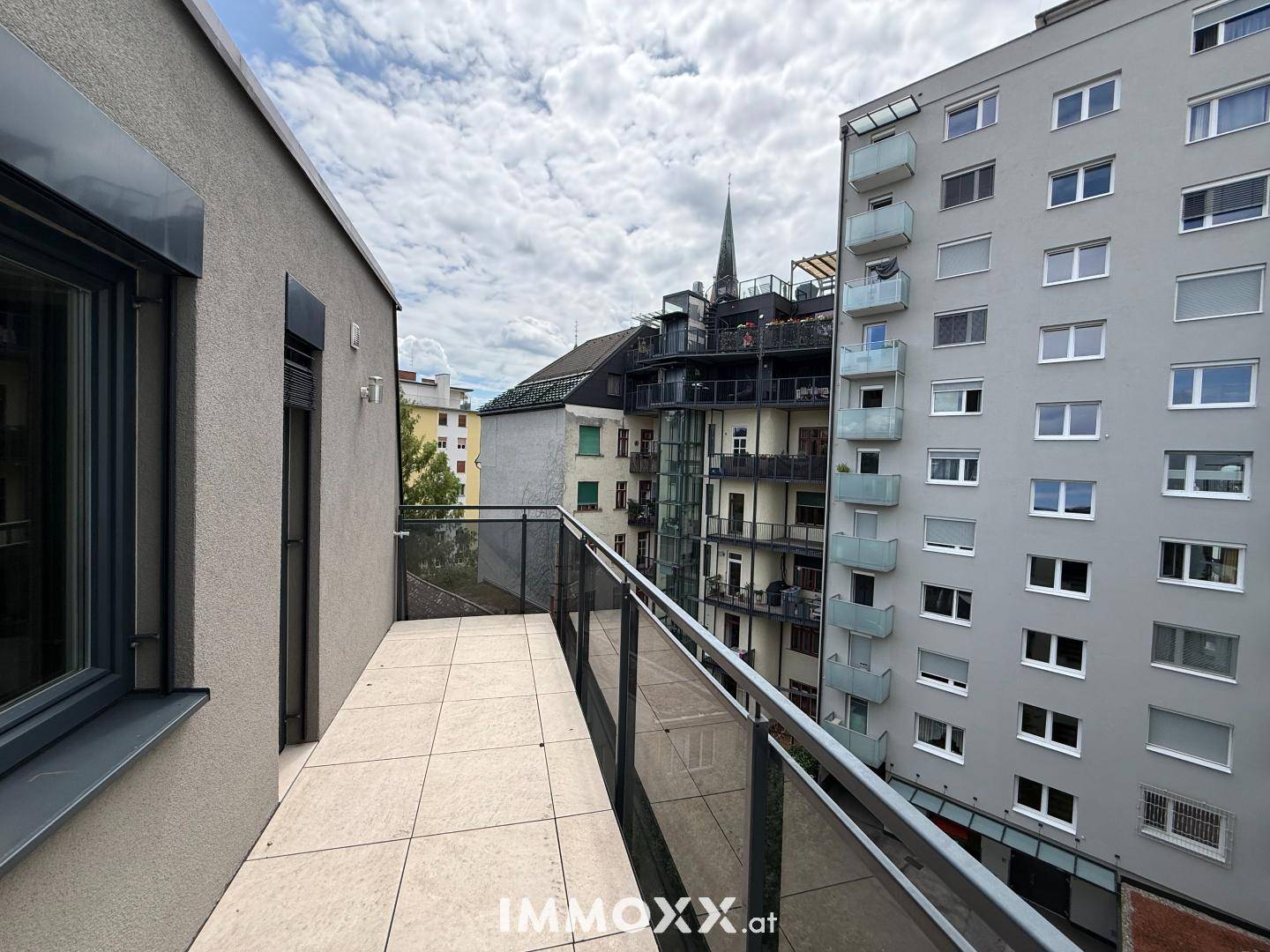 Schmaler Balkon mit Fliesenboden und Blick auf die umliegende städtische Architektur.