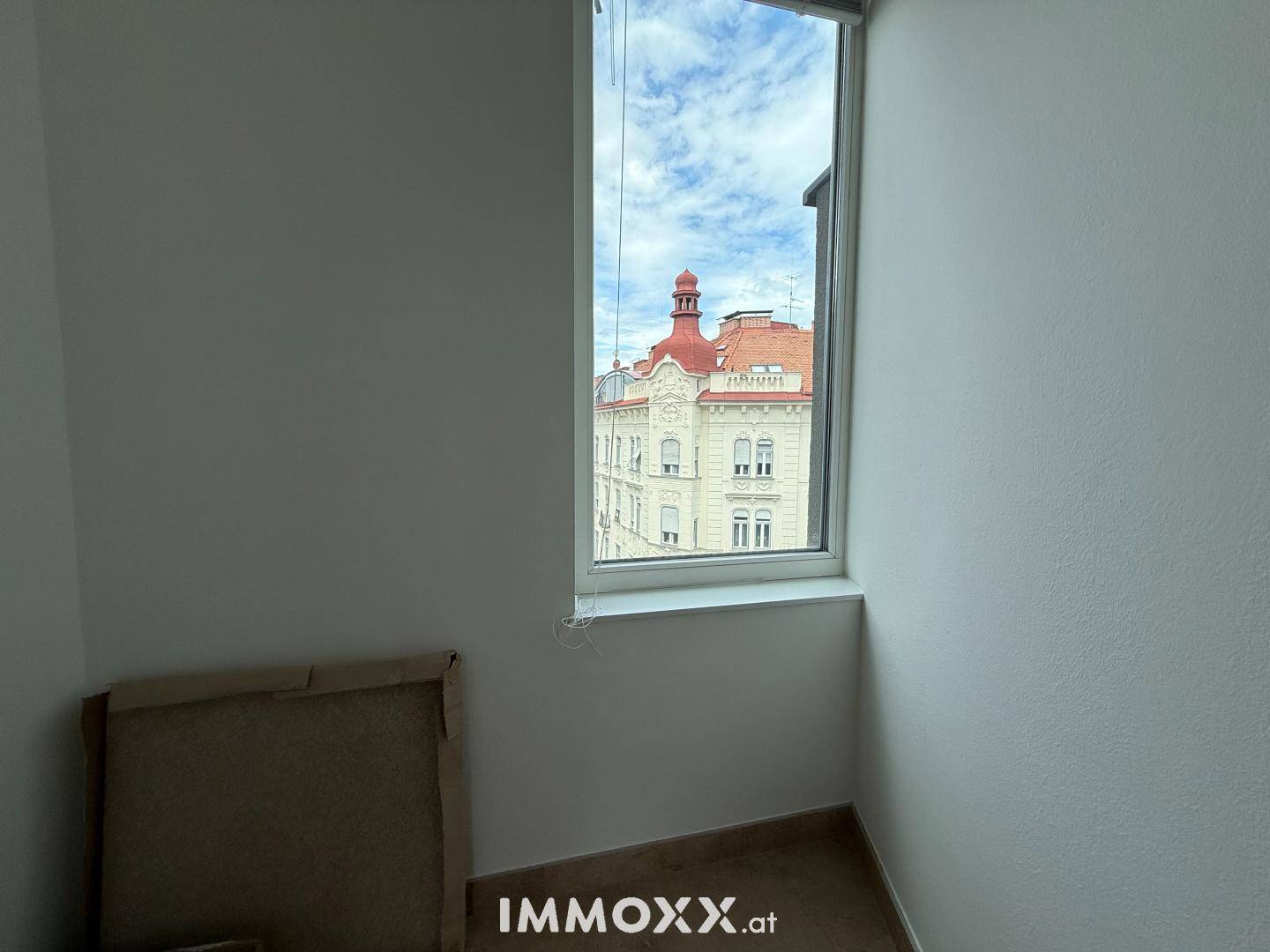 Blick aus dem Fenster auf ein charmantes Altbaugebäude mit markantem roten Dach.