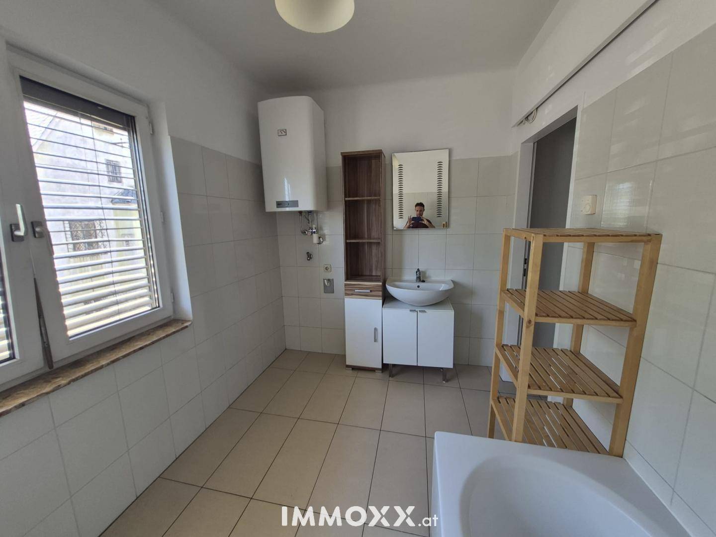 Badezimmer mit Waschbecken, Spiegelschrank, Warmwasserboiler und gefliesten Wänden und Boden.