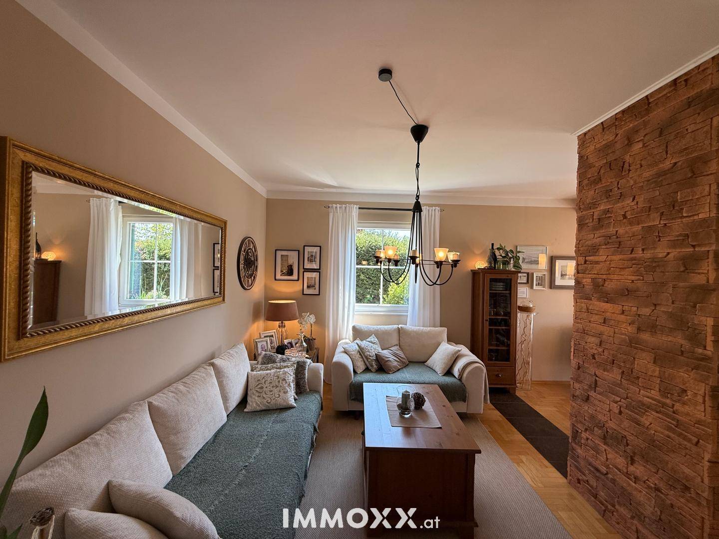 Wohnzimmer mit beiger Wandfarbe, großem Spiegel, bequemen Sofas und dekorativer Steinwand.