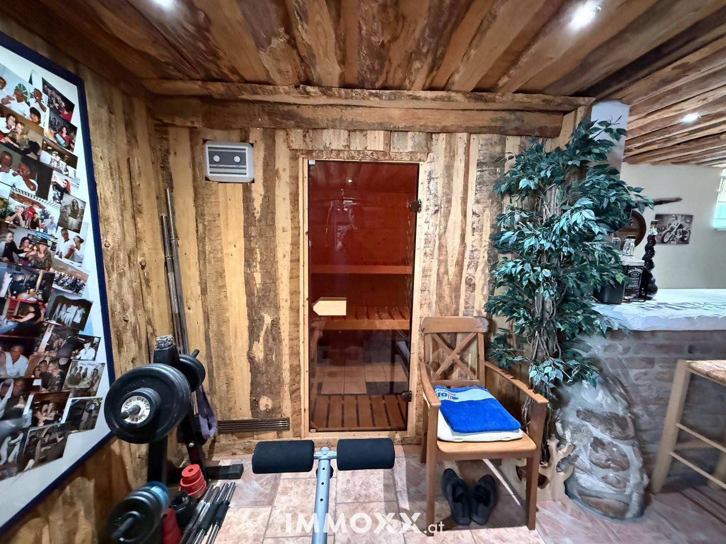 Rustikaler Kellerraum mit Sauna, Fitnessgeräten und Holzverkleidung an Wänden und Decke.