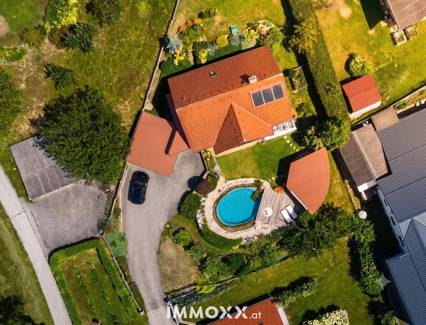 Luftaufnahme des Anwesens mit Haus, Garten, Pool und umliegender grüner Landschaft.