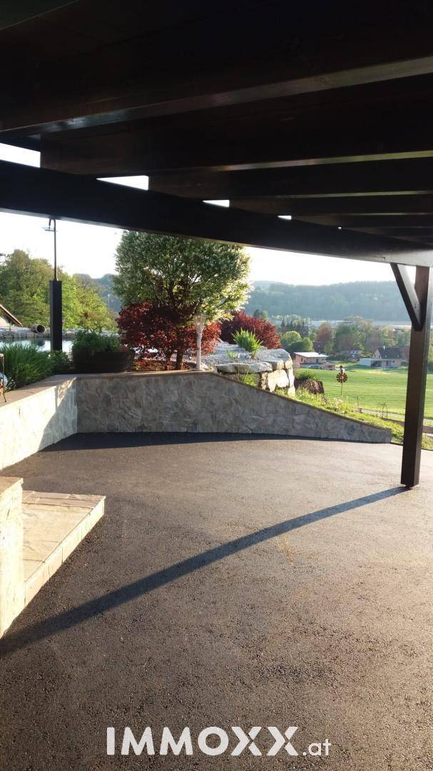 Überdachter Parkplatz mit asphaltierter Auffahrt und weitem Blick auf die umliegende Landschaft.