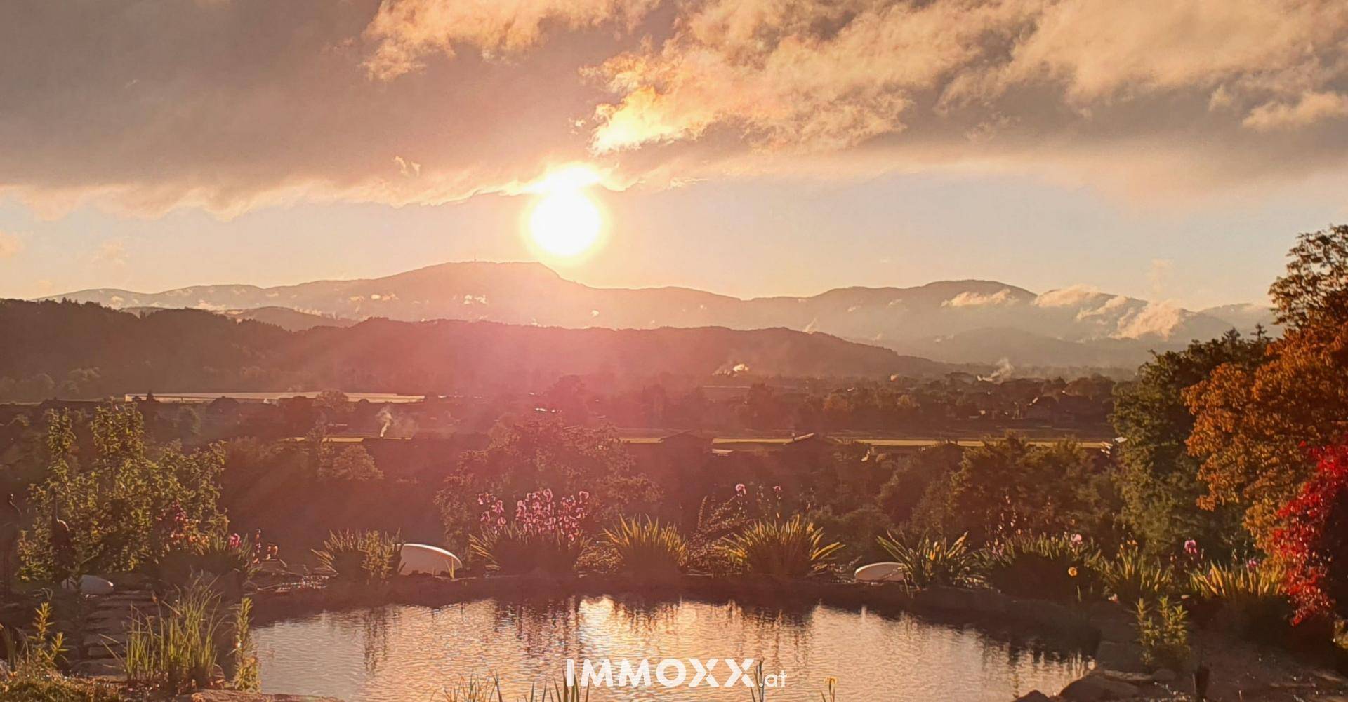 Atemberaubender Sonnenuntergang über dem Naturpool im Garten mit malerischem Blick auf die Berglandschaft.