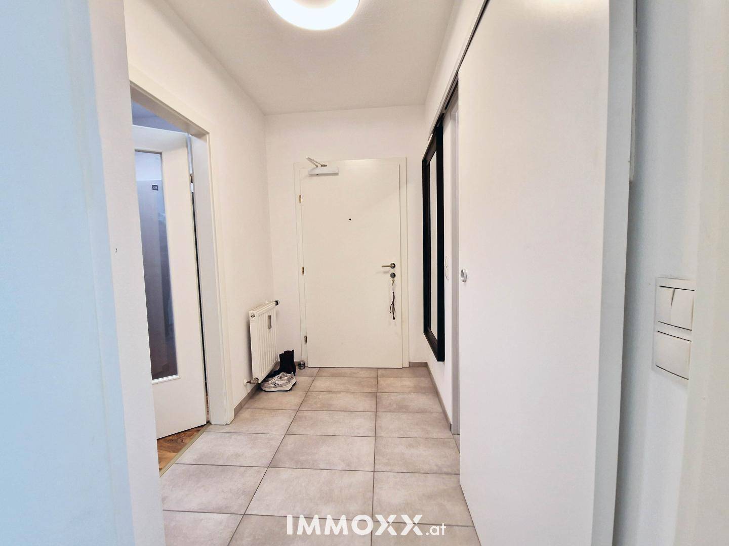 Heller Eingangsbereich mit Fliesenboden, Garderobe und Zugang zu weiteren Räumen.
