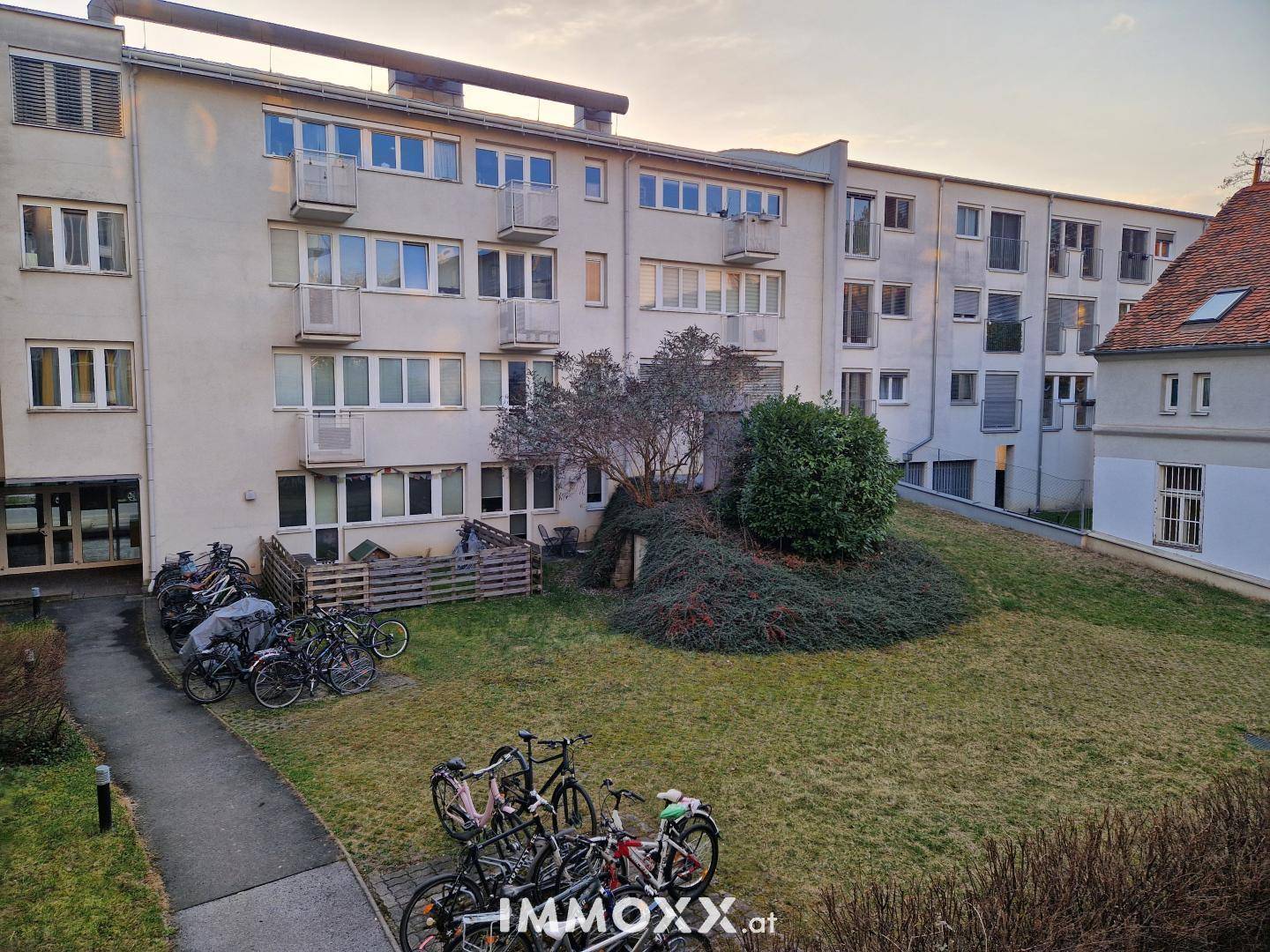 Außenansicht eines Mehrfamilienhauses mit Grünfläche und Fahrradabstellplätzen.