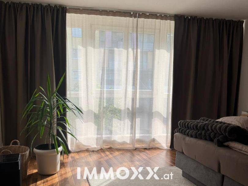 Großes Fenster im Schlafzimmer mit Vorhängen, das viel Tageslicht hereinlässt.