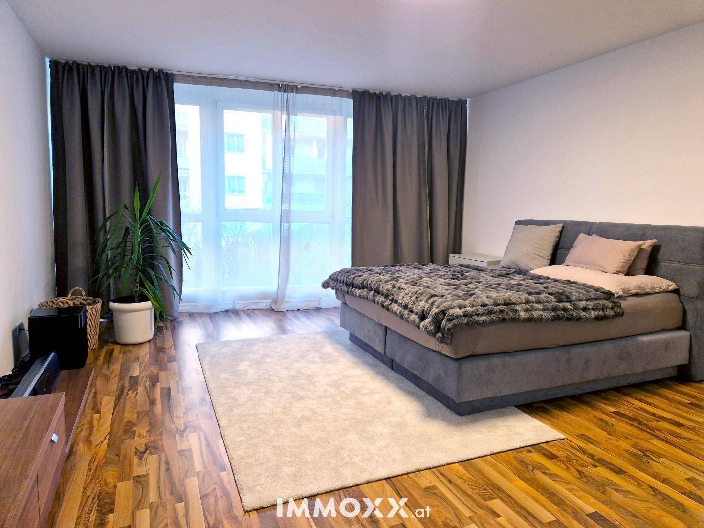 Gemütliches Schlafzimmer mit Holzboden, großem Fenster und bequemen Doppelbett.