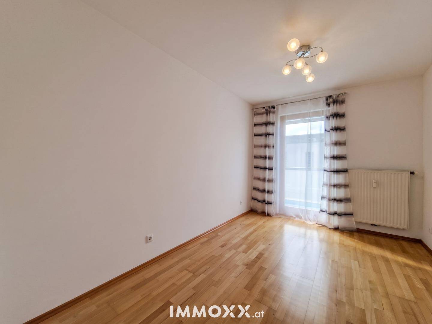 Geräumiges Schlafzimmer mit Parkettboden, großem Fenster und viel Tageslicht.