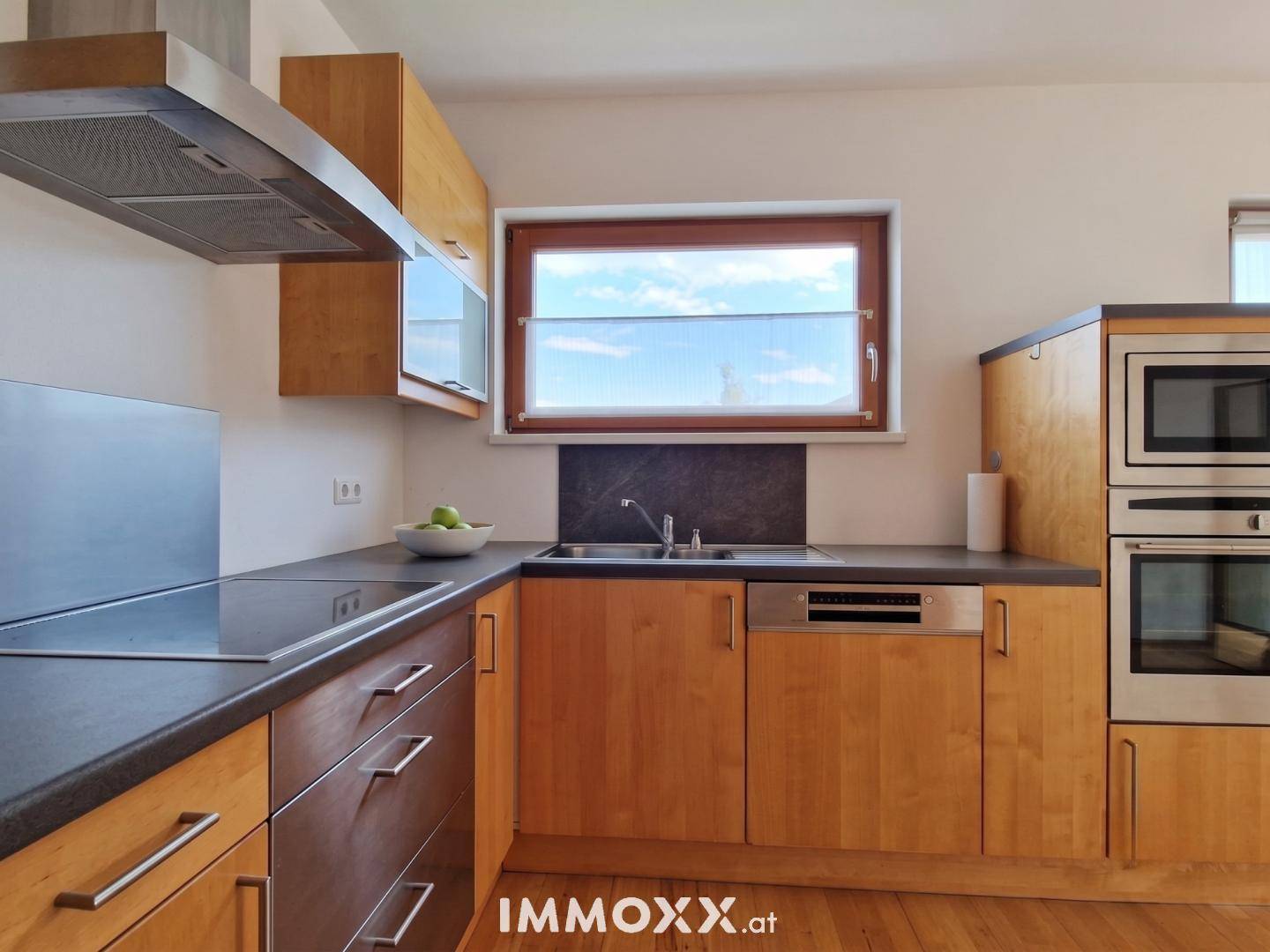 Funktionale Holzküche mit Einbaugeräten, Spülmaschine und Fenster mit Ausblick.