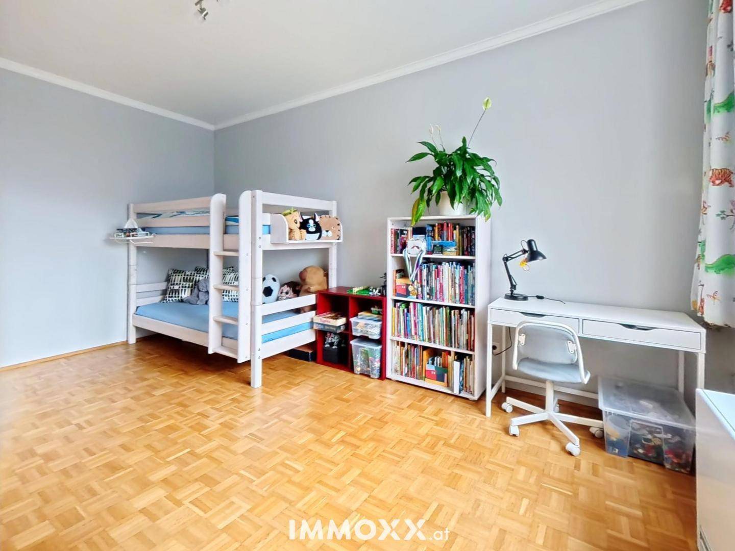 Kinderzimmer mit Etagenbett, Schreibtisch, Bücherregalen und hellem Parkettboden.