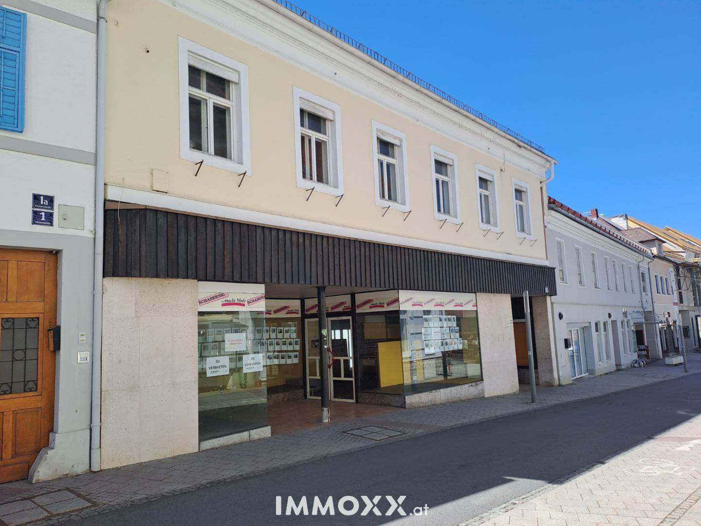 Die Vorderansicht des Gebäudes mit großen Schaufenstern und traditioneller Architektur.