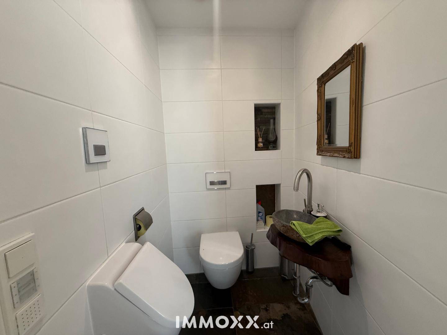 Modernes Gäste-WC mit weißen Fliesen, wandhängendem WC und einem einzigartigen Waschbecken.