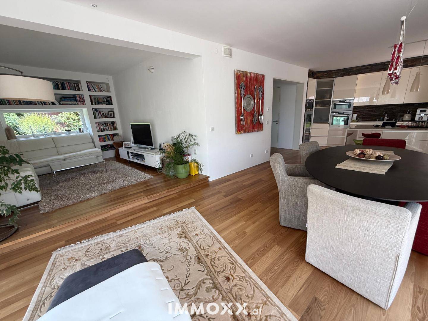 Geräumiger Wohnbereich mit bequemer Couch, integriertem Bücherregal und Holzfußboden.