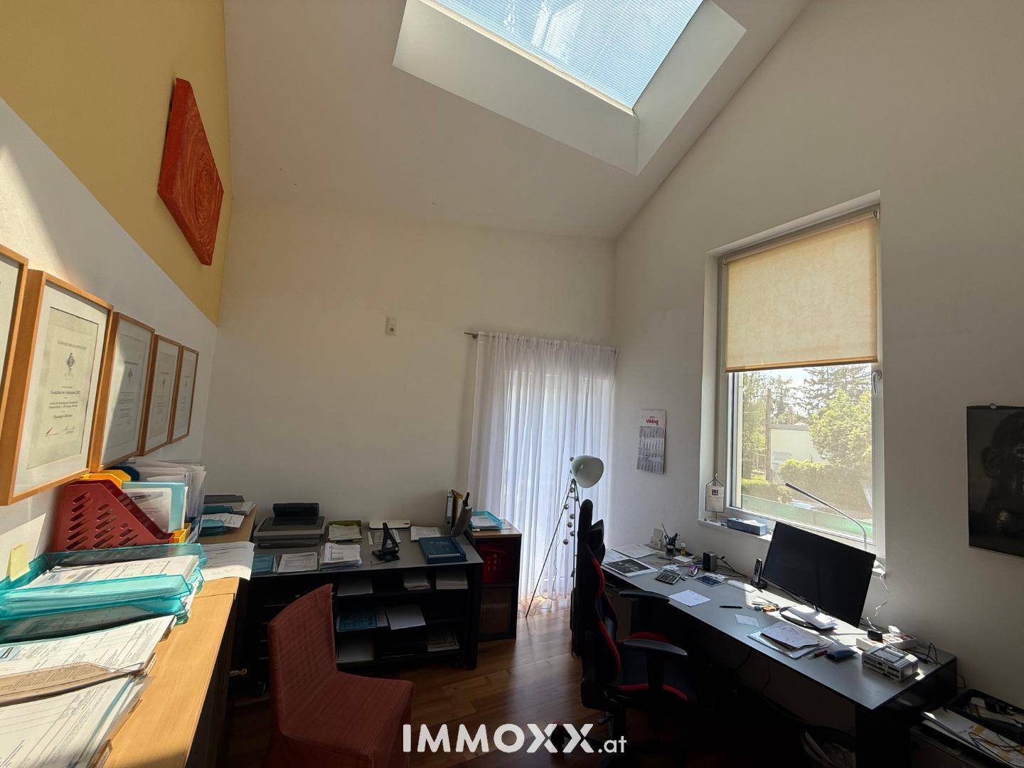 Helles Arbeitszimmer mit Schreibtisch, Regalen und viel Tageslicht durch das Oberlicht.