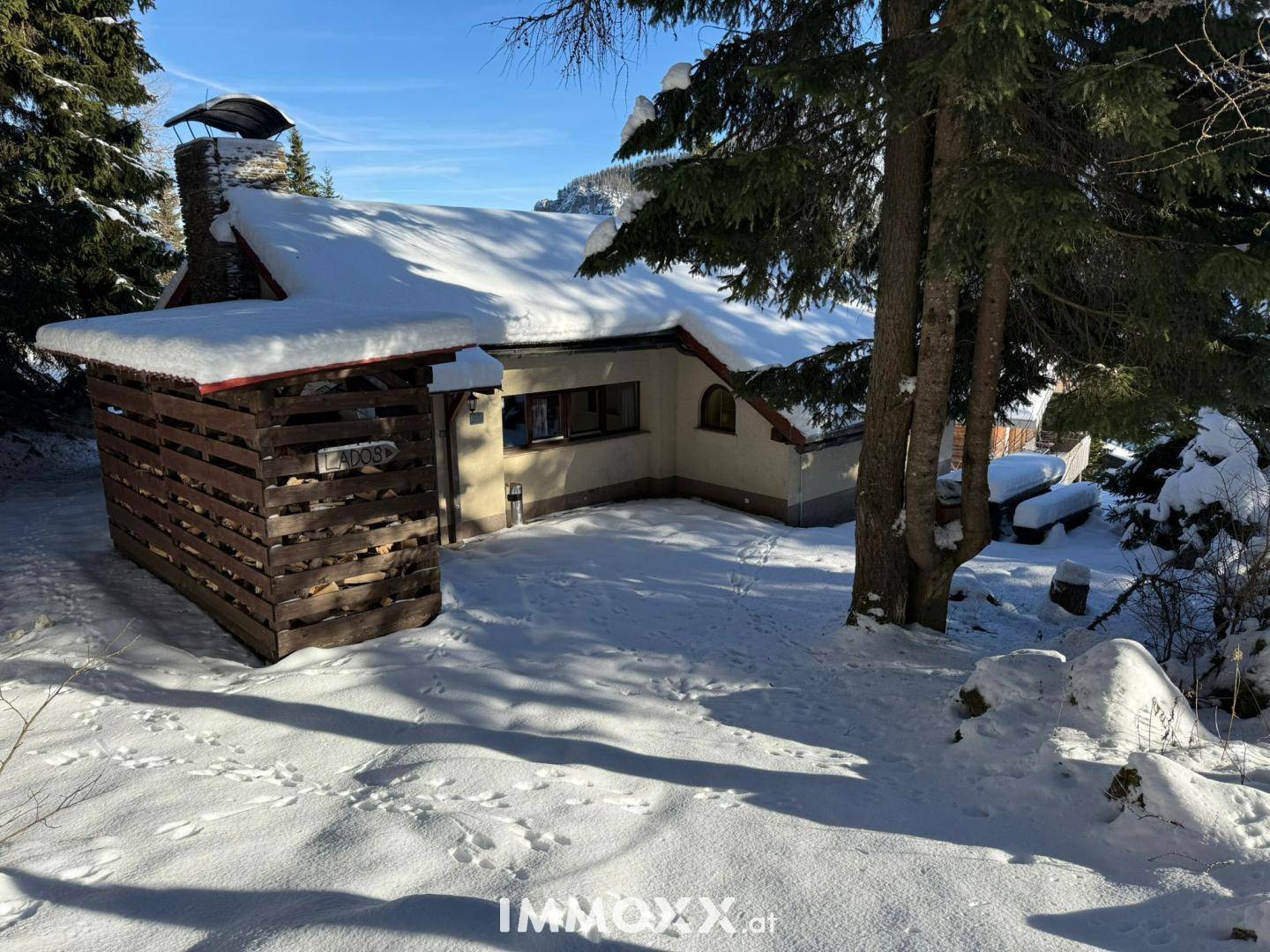 Außenansicht des Hauses im Winter mit verschneitem Dach und einem Holzschuppen.