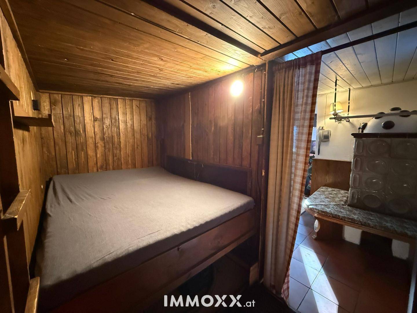 Kleines Schlafzimmer mit Holzwänden und -decke, integriert in den Wohnbereich.