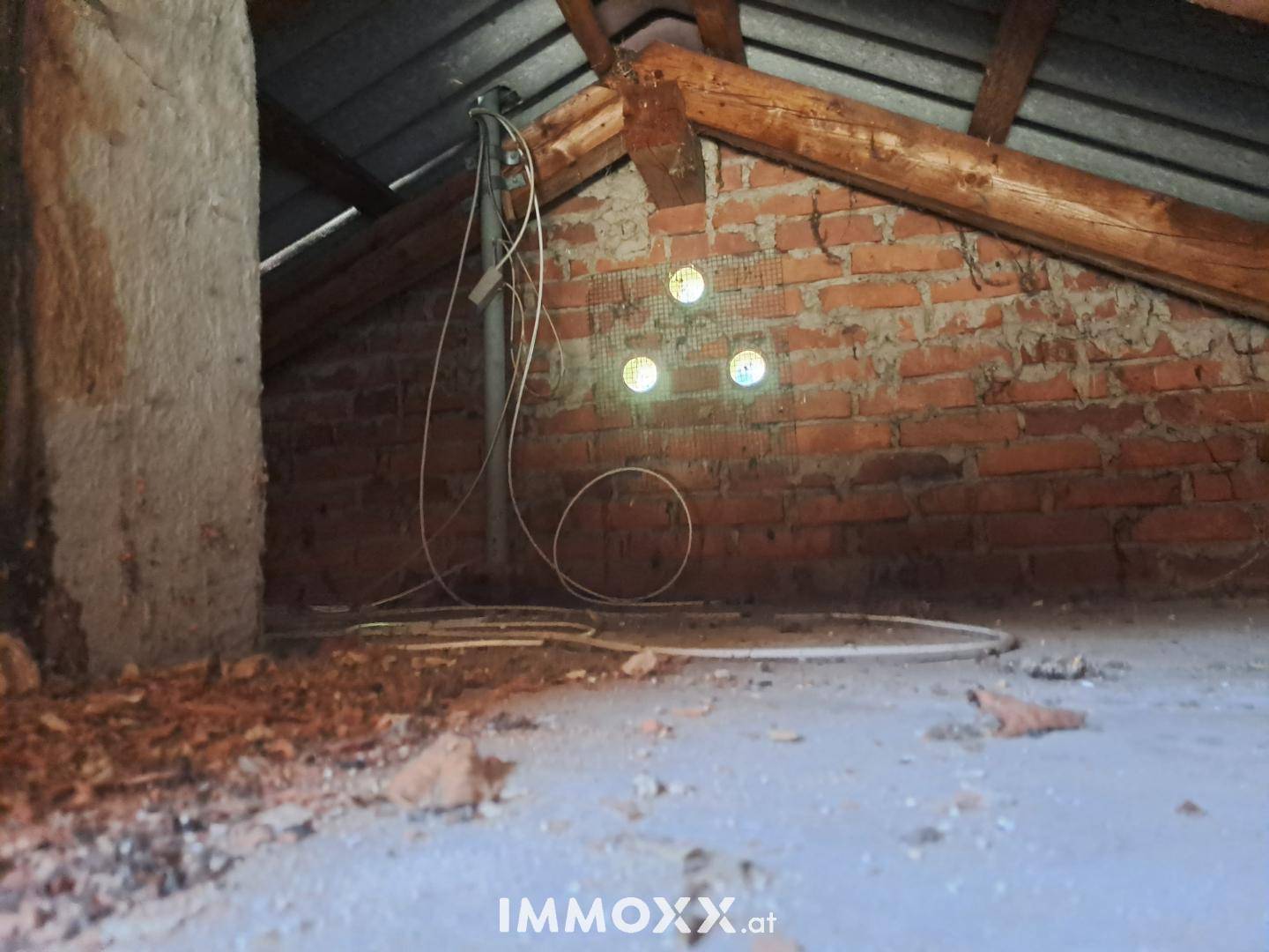 Unausgebauter Dachboden mit sichtbaren Holzbalken und Ziegelwänden, ideal für Ausbau.