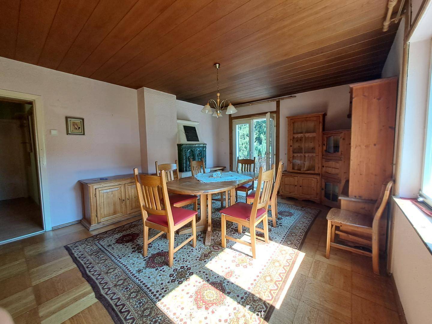 Gemütlicher Essbereich mit rustikalen Holzmöbeln, Kachelofen und viel Tageslicht.